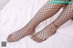 A woman in fishnet stockings laying on a bed.