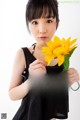 A young woman holding a yellow flower in her hand.