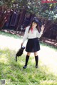 A woman in a white shirt and black skirt holding a black bag.