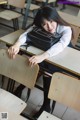 A woman sitting at a desk in a classroom.