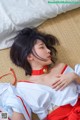 A woman laying on top of a bed wearing a red and white dress.