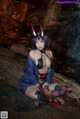 A woman dressed as a demon sitting on a rock.