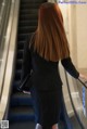 A woman in a business suit is walking down an escalator.