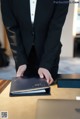 A man in a tuxedo standing at a desk with a laptop.