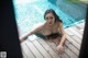 A naked woman laying on the edge of a swimming pool.