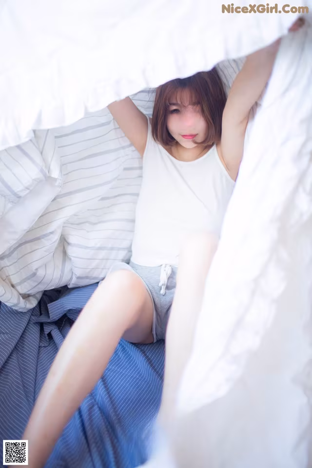 A woman laying in bed under a white sheet.