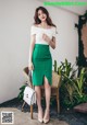 a woman in a white top and green skirt