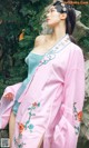 A woman in a pink and blue dress posing for a picture.