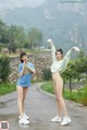 A couple of women standing next to each other on a road.