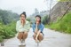 Two young women sitting on the side of a road.