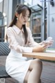 A woman sitting at a table looking at her phone.