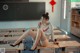 A woman sitting on top of a desk in a classroom.