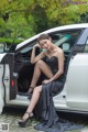 A woman in a black dress sitting in the back of a white car.