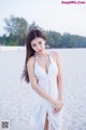 A woman in a white dress standing on a beach.