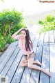 A woman sitting on a wooden deck with her legs crossed.