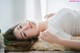 A woman laying on a bed with a flower in her hand.