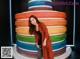 A woman standing in front of a large rainbow cake.