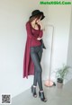 A woman wearing black leather pants and a burgundy cardigan.