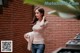 A woman standing in front of a brick wall.