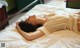 A woman laying on top of a bed in a white dress.