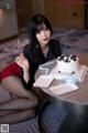 A woman sitting at a table with a cake and a knife.