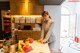 A woman standing in a kitchen next to a table with a plate of fruit.