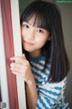 A young woman leaning against a red door.