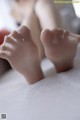 A close up of a pair of feet on a bed.