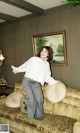 A woman standing on top of a couch in a living room.