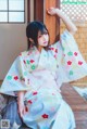 A woman in a kimono sitting on a wooden bench.