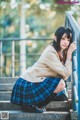 A woman in a school uniform crouching down on some steps.