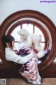 A woman sitting on a window sill holding a teddy bear.