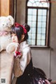 A girl sitting on a window sill holding a teddy bear.