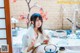 A woman in a kimono sitting at a table with a teapot.