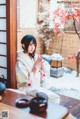 A woman in a kimono sitting on a wooden table.