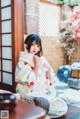 A woman in a kimono sitting on a wooden table.