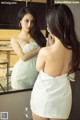 A woman in a white dress looking at herself in the mirror.