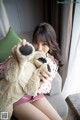 A woman sitting on a couch holding a teddy bear.