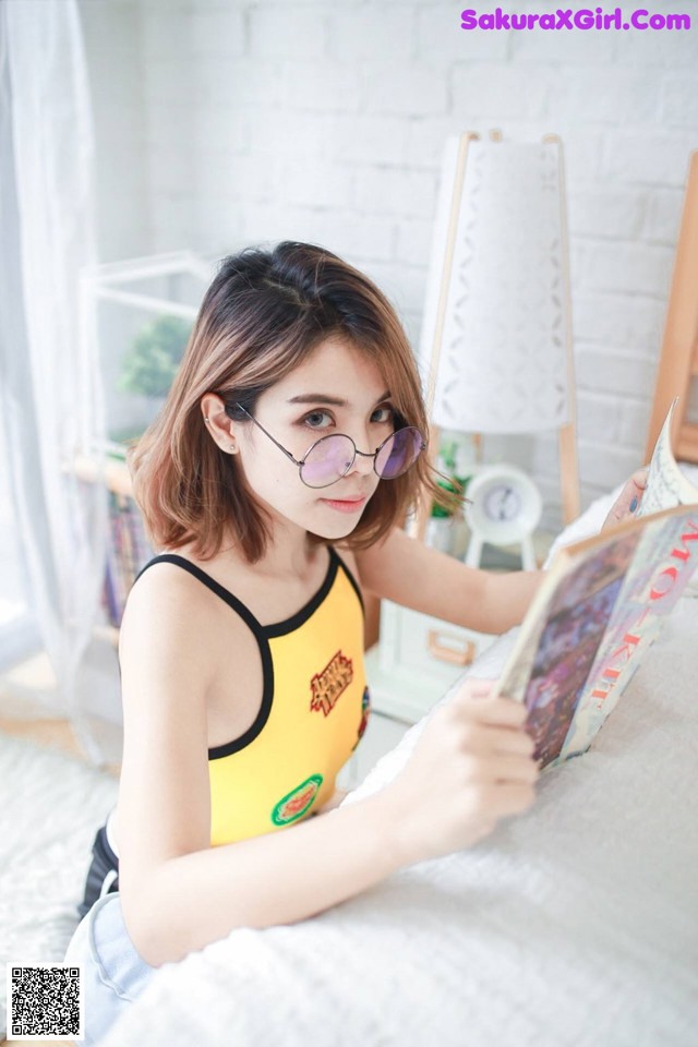 A woman sitting on a bed reading a book.