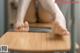 A woman sitting on top of a wooden desk with her feet on the table.