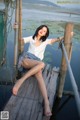 A woman sitting on a wooden dock by the water.