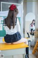 A woman in a school uniform sitting on a desk.