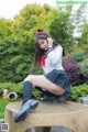 A woman in a school uniform sitting on a bench.