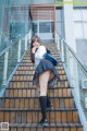 A woman in a school uniform is standing on some stairs.