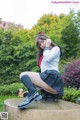 A woman in a school uniform sitting on a stone bench.