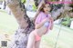 A woman in a pink bikini standing next to a tree.