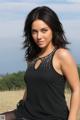 A woman in a black dress sitting on a grassy field.