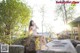 A woman in a white bikini sitting on a rock.