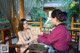 A woman sitting at a table talking to another woman.