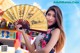 A woman in a cheongsam holding a yellow fan.